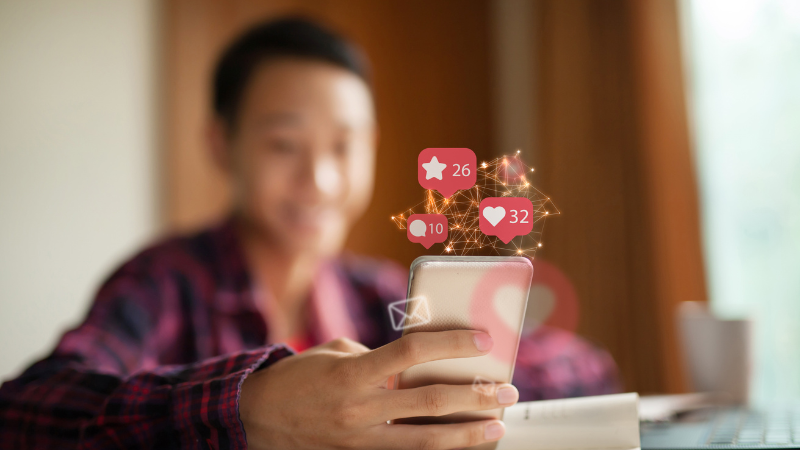 A person engaging with social media on a smartphone with likes, stars, and notifications floating above, illustrating how data-driven content shared across search and social boosts brand reach — as practiced by Clicks Gorill, Kolkata's top SEO company.