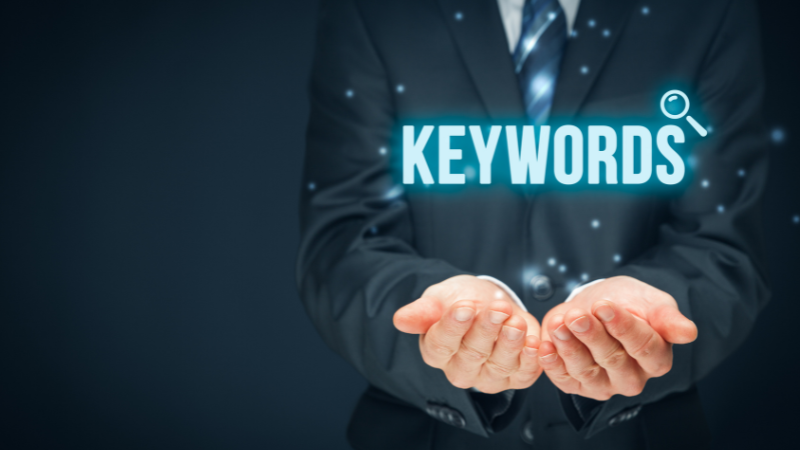 Clicks Gorilla Google Ads Keyword Research and Targeting Strategy A professional in a suit holding a glowing "KEYWORDS" graphic, symbolizing the strategic keyword research and targeting provided by Clicks Gorilla for Google Ads campaigns.